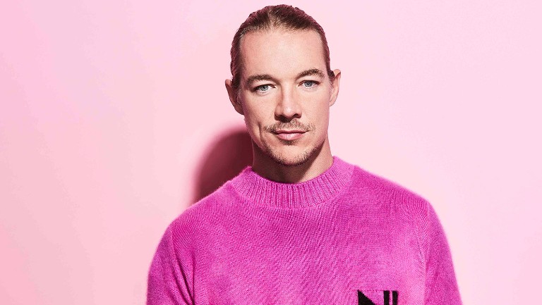 DJ Diplo berfoto di depan background berwarna pink dengan sweater pink